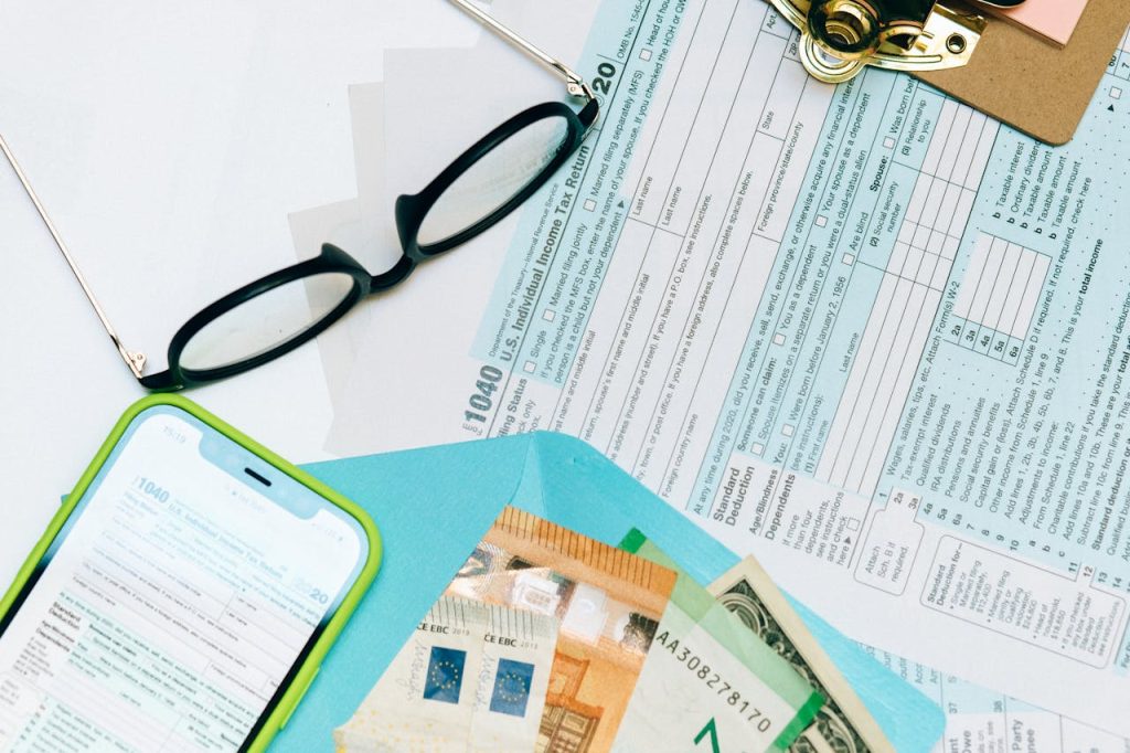income-tax-return-form-beside-black-eyeglasses-8927649 Close-up of tax forms, smartphone, and dollar bills for financial analysis and preparation.